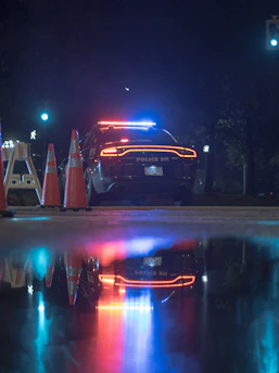 A close-up of a police radio and flashing blue lights at night