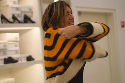 A customer happily trying on a sporty sweatshirt in a cozy store corner.