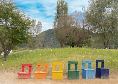 A colorful picnic scene featuring multiple foldable chairs around a wooden table.