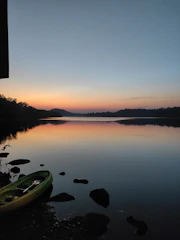 a kayak sitting on the shore of a lake at sunset