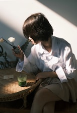 a woman sitting at a table with a flower in her hand