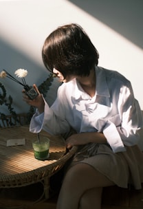 a woman sitting at a table with a flower in her hand