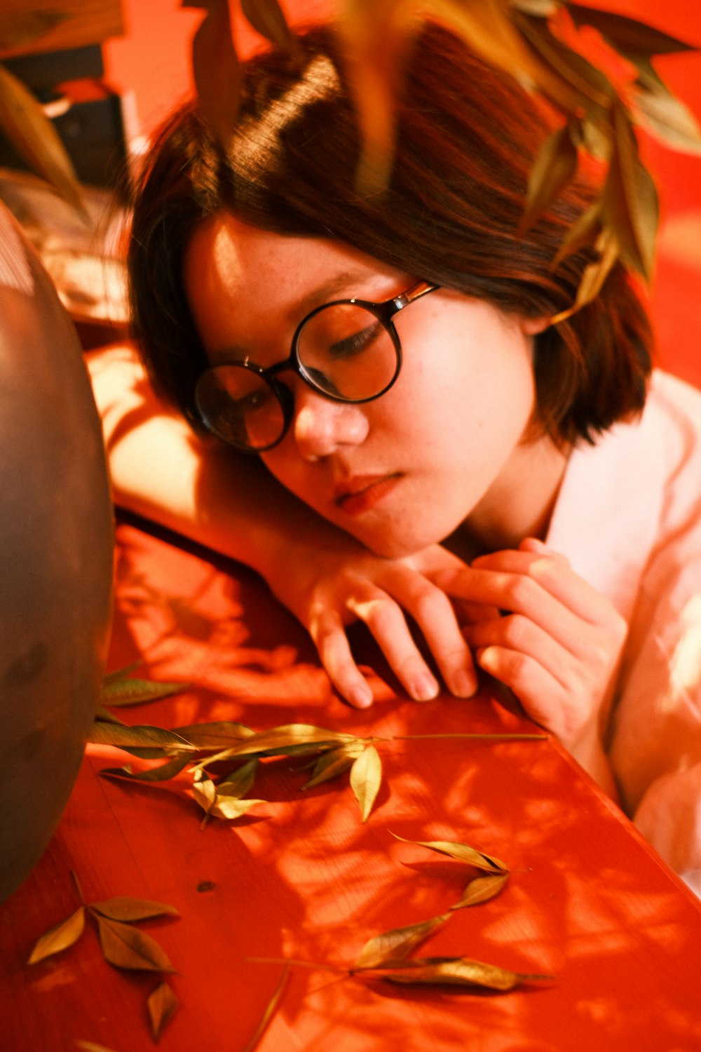 a woman wearing glasses laying on a red table