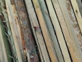 A collection of wooden planks with various textures and colors, ranging from light beige to dark brown, laid out side by side in an overlapping pattern.