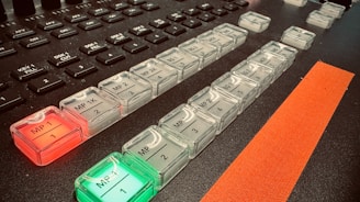 A close-up of a control panel featuring rows of illuminated buttons with labels such as 'MP 1K', 'MP 2', and others. The buttons are backlit with red and green lights. There are additional unlit keys above the buttons, which appear darker. A prominent orange strip runs alongside the buttons, adding a contrasting element.