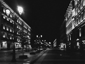 Black and white photograph of an old city street illuminated by lamplight.