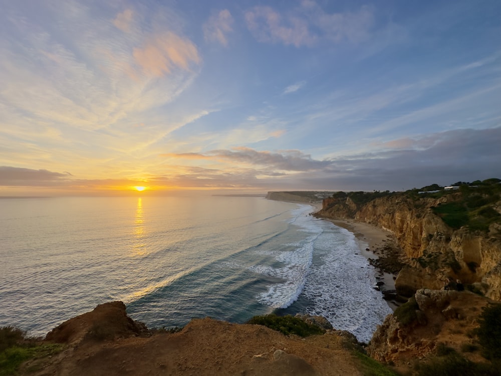 the sun is setting over the ocean on the coast