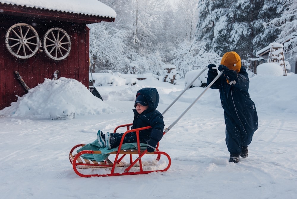 a young boy is pulling a sled in the snow