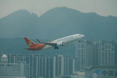 Airplane taking off over Guangzhou city skyline at sunrise.