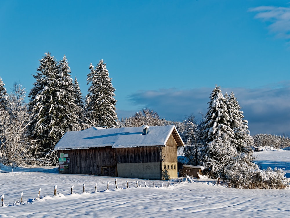 a snow covered field with a barn and trees