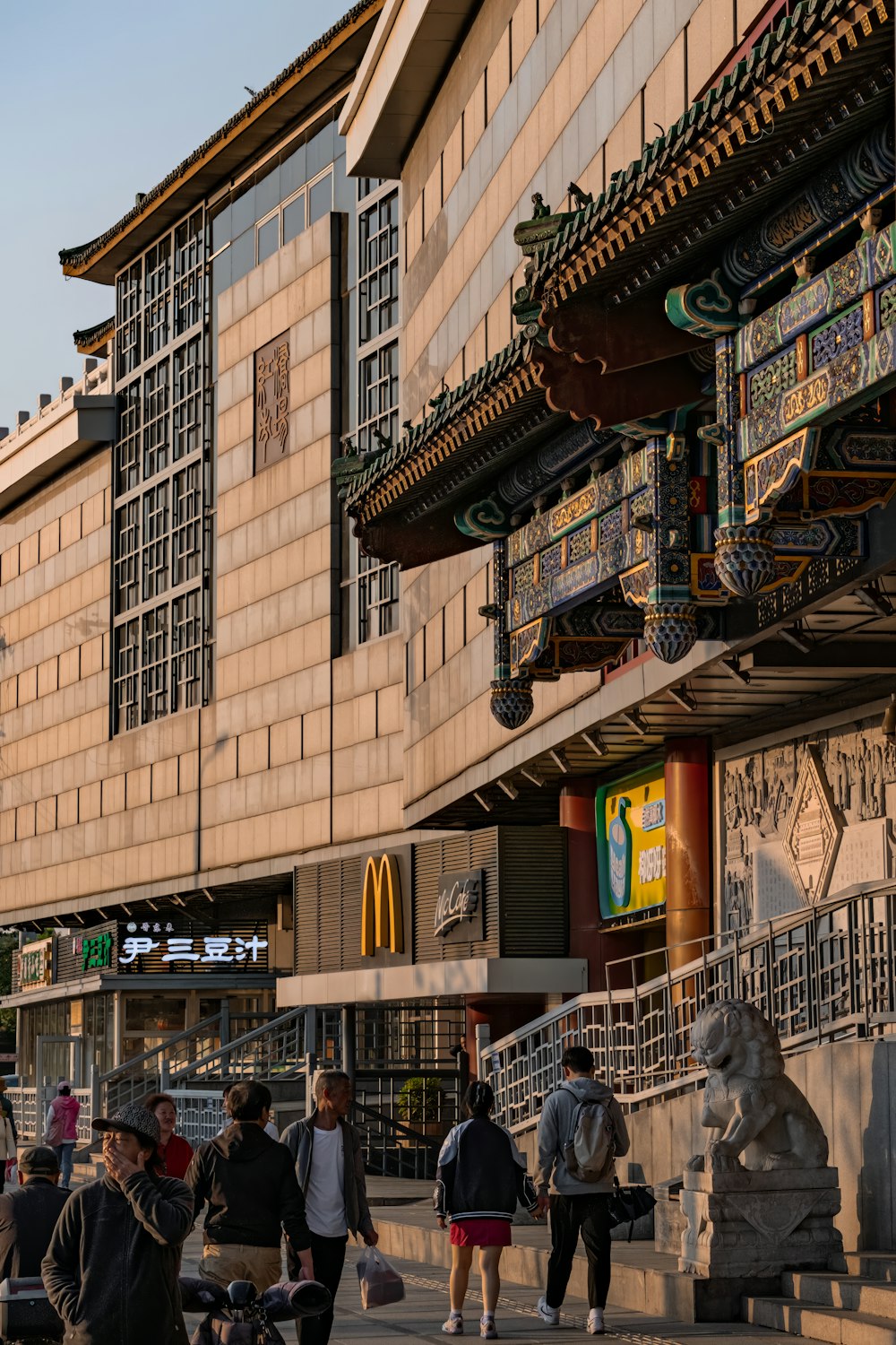 a group of people walking down a street next to a tall building