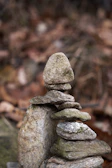 Smooth river stones stacked gently on a muted taupe background, embodying balance and calm.
