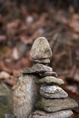 Smooth river stones stacked gently on a muted taupe background, embodying balance and calm.