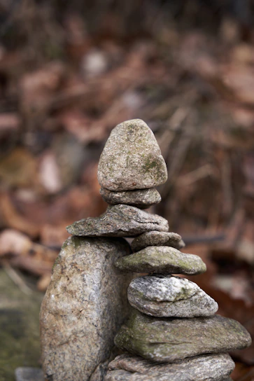 A charming stack of smooth, colorful pebbles balanced gently on a soft cream background.