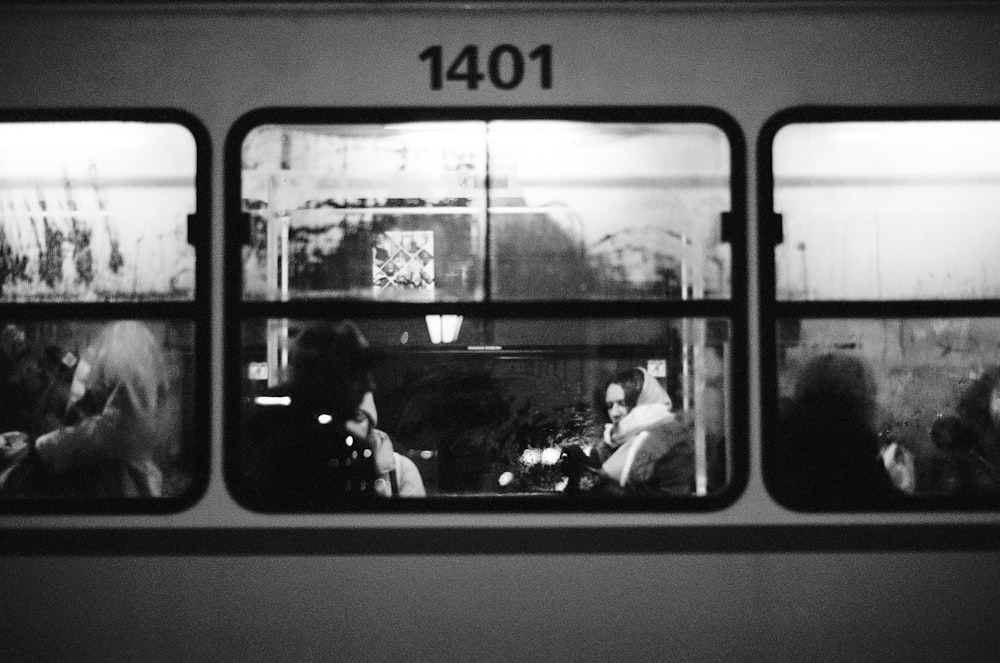 a black and white photo of people sitting on a bus