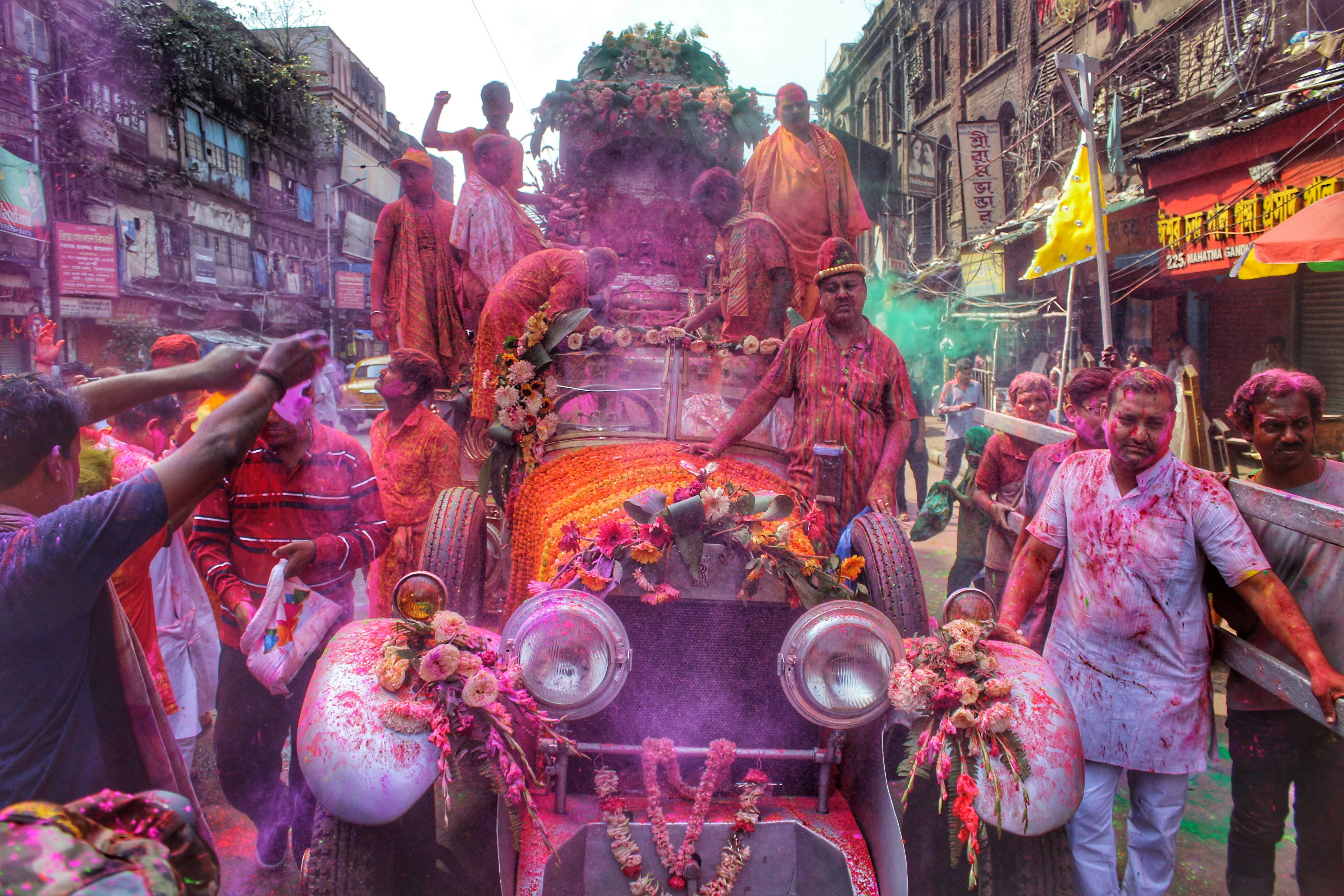 a group of men standing around a car covered in colored powder
