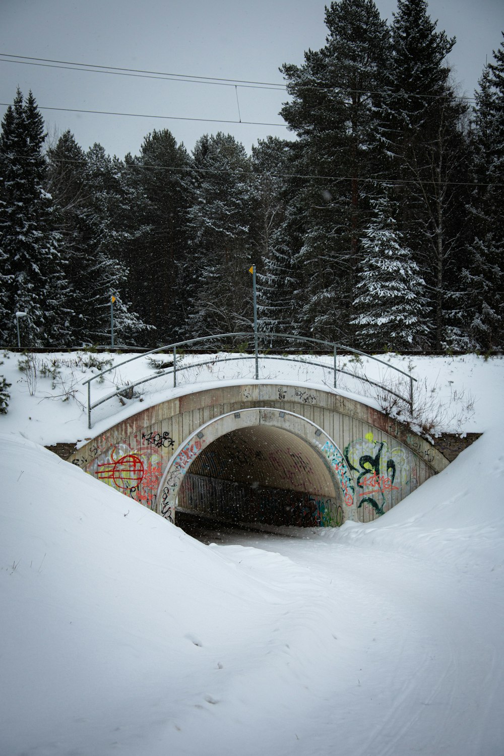 a snow covered bridge with graffiti on it