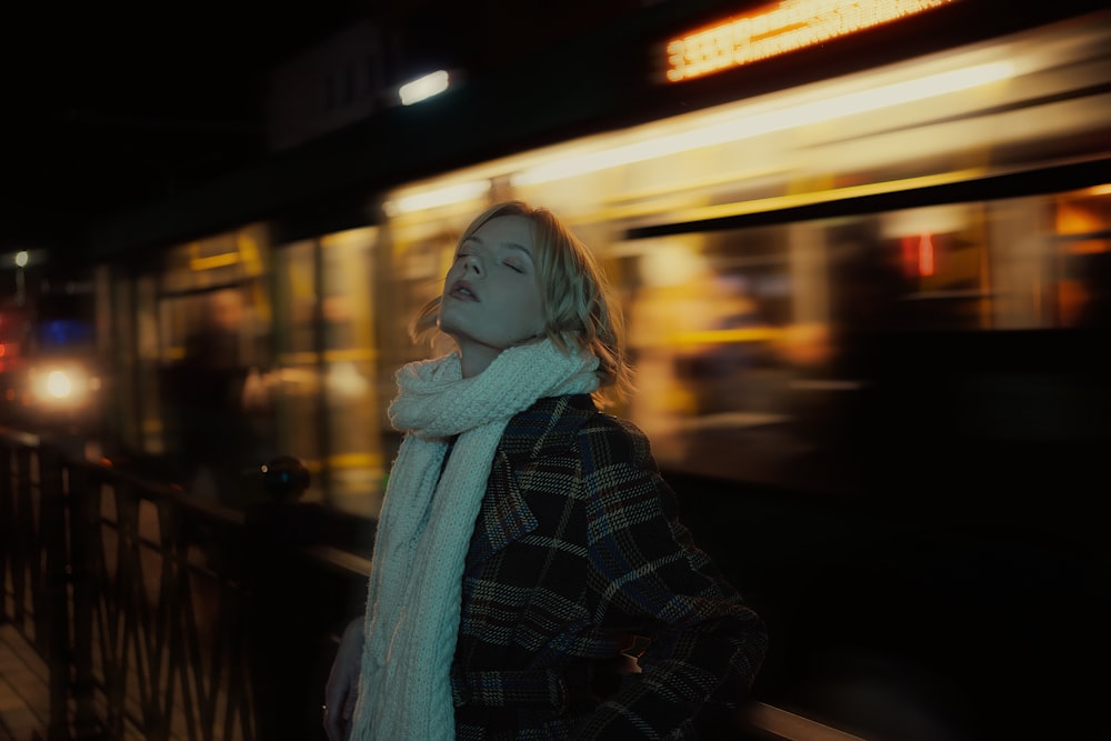 a woman standing in front of a train at night