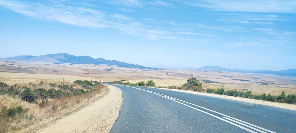 a road in the middle of the desert with mountains in the background