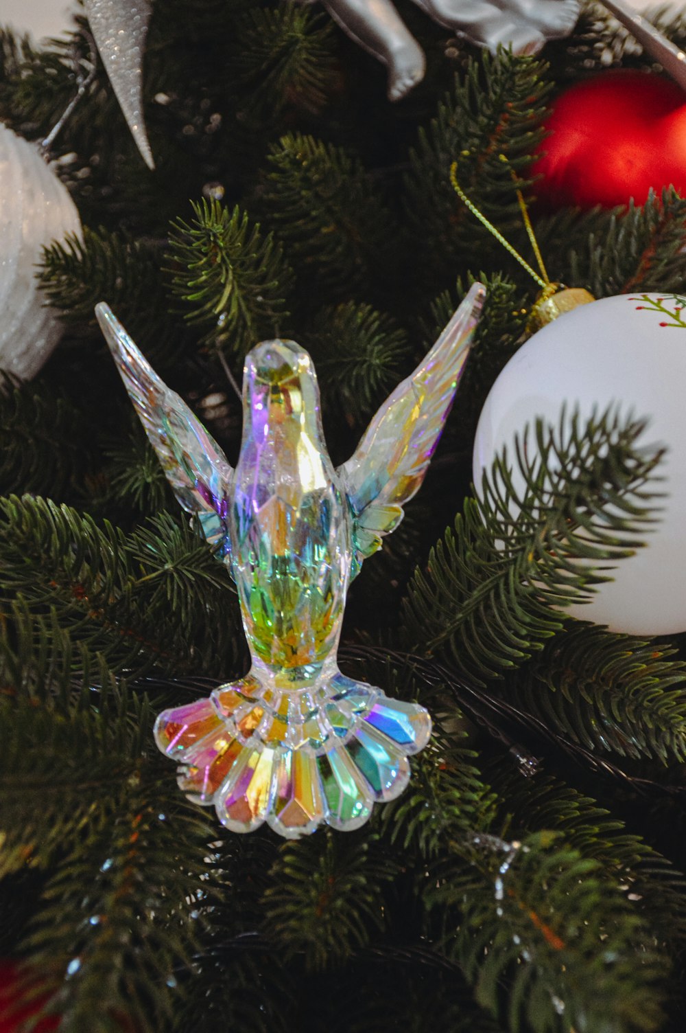 a glass angel ornament sitting on top of a christmas tree