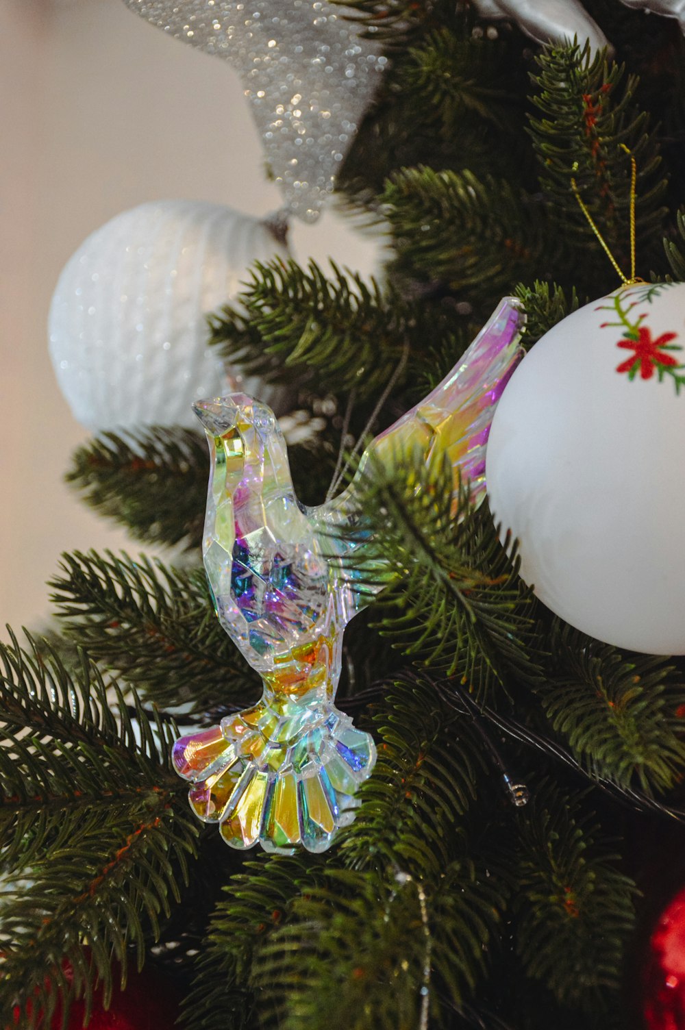 a glass bird ornament hanging from a christmas tree