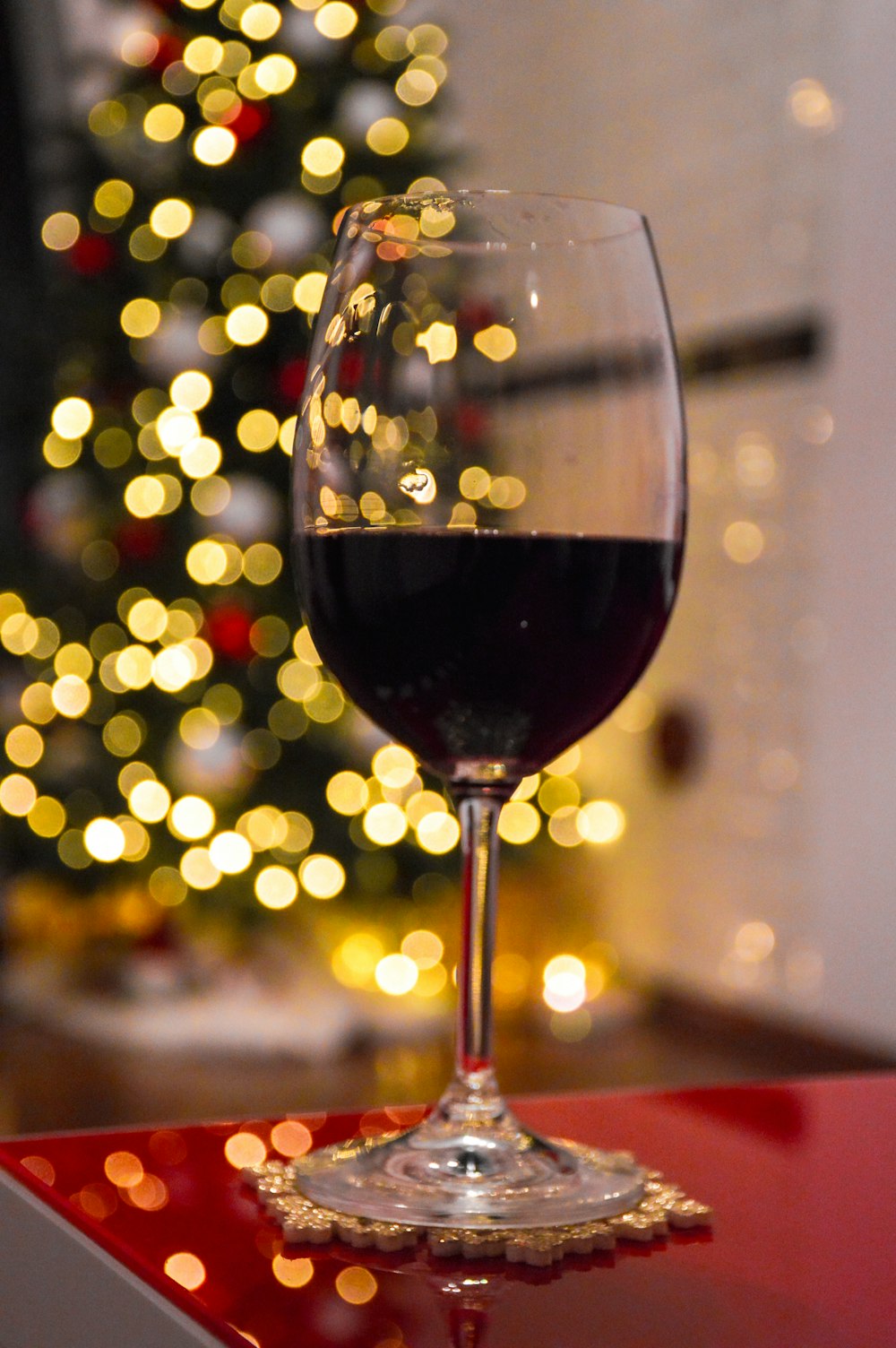 a glass of wine sitting on a table next to a christmas tree