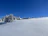 A peaceful lakeside cottage surrounded by snow-covered trees under a clear blue sky.