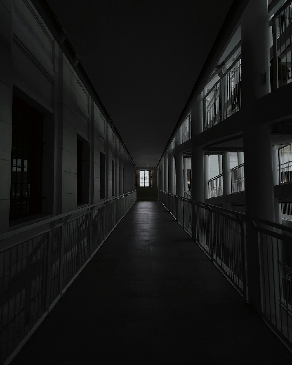 a long dark hallway with windows and railings