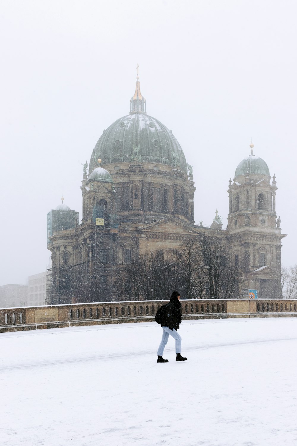 a person walking in the snow in front of a building