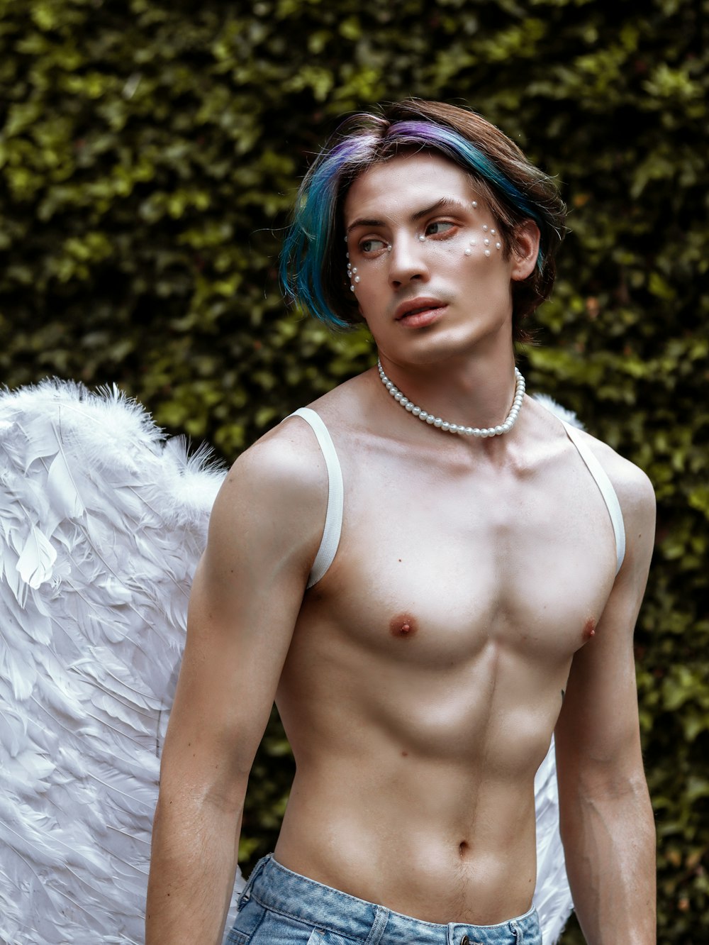 a shirtless man with blue hair and white wings