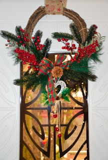 A festive wreath made from natural fibers and vibrant recycled paper, hanging on a rustic wooden door.