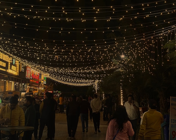 A lively street scene in Lubbock with people enjoying a local outdoor event under string lights.