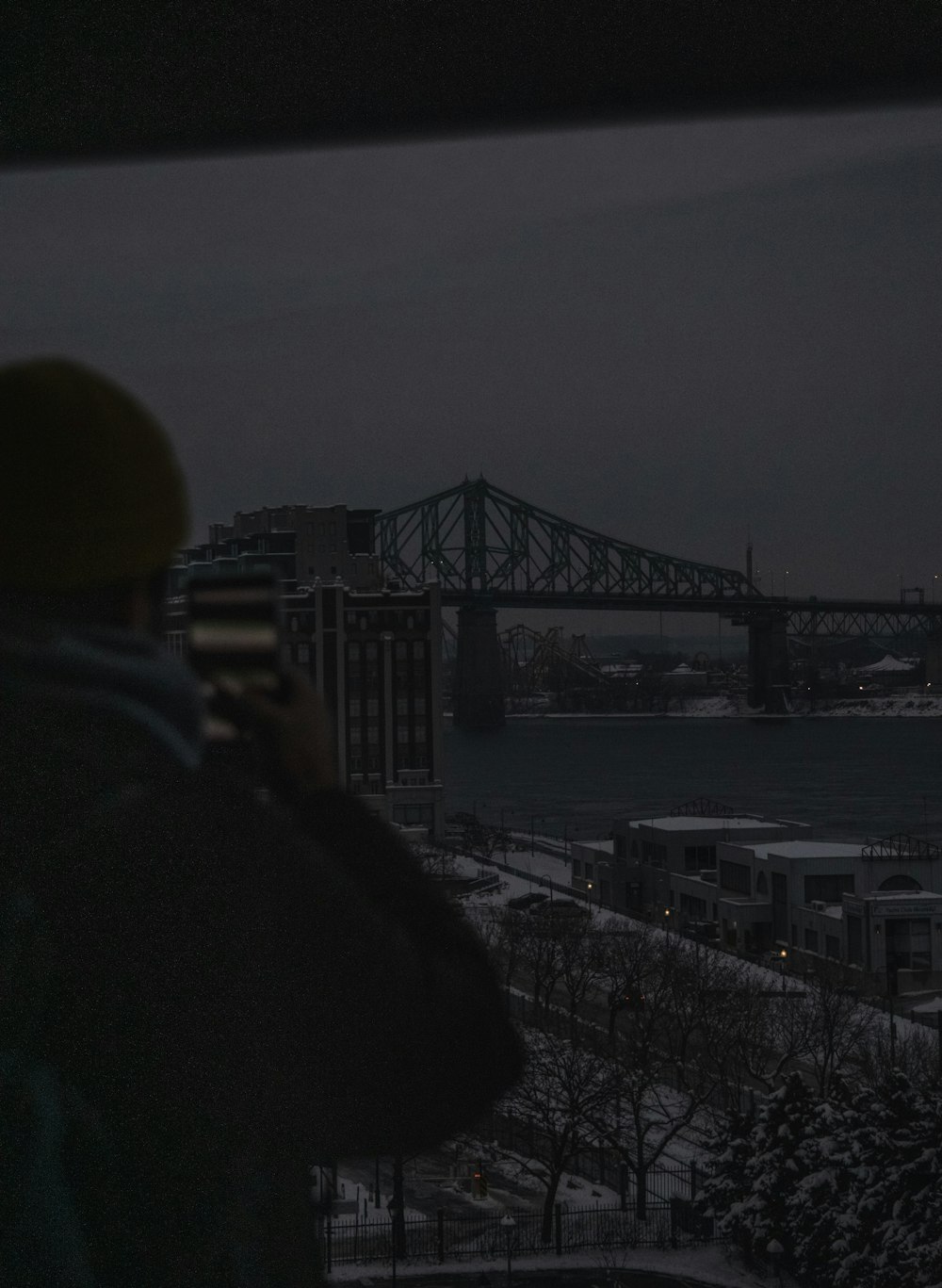 a man standing in front of a window looking out at a bridge