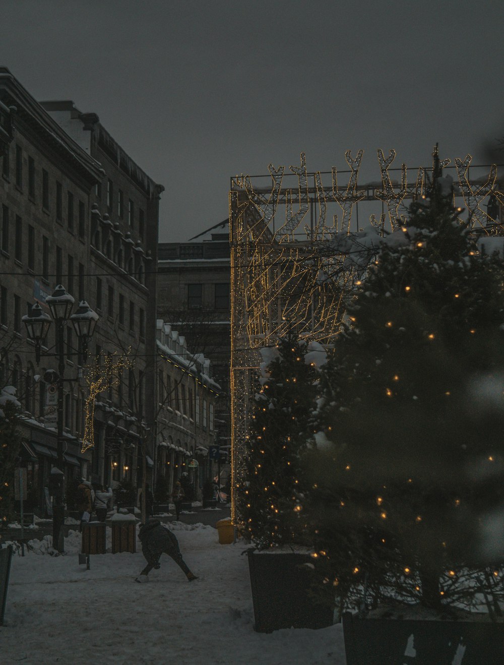a snowy city street at night with a lit christmas tree