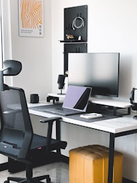A clean, modern workspace featuring a sleek office chair next to a laptop and shipping boxes.