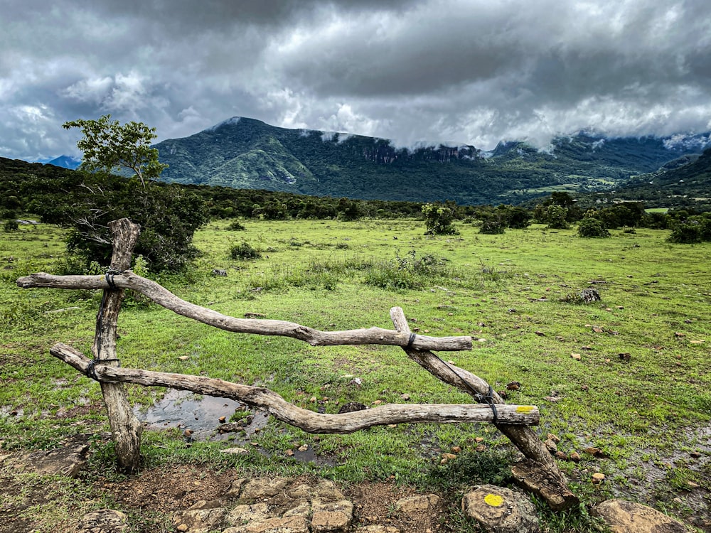 a wooden fence in a field with mountains in the background