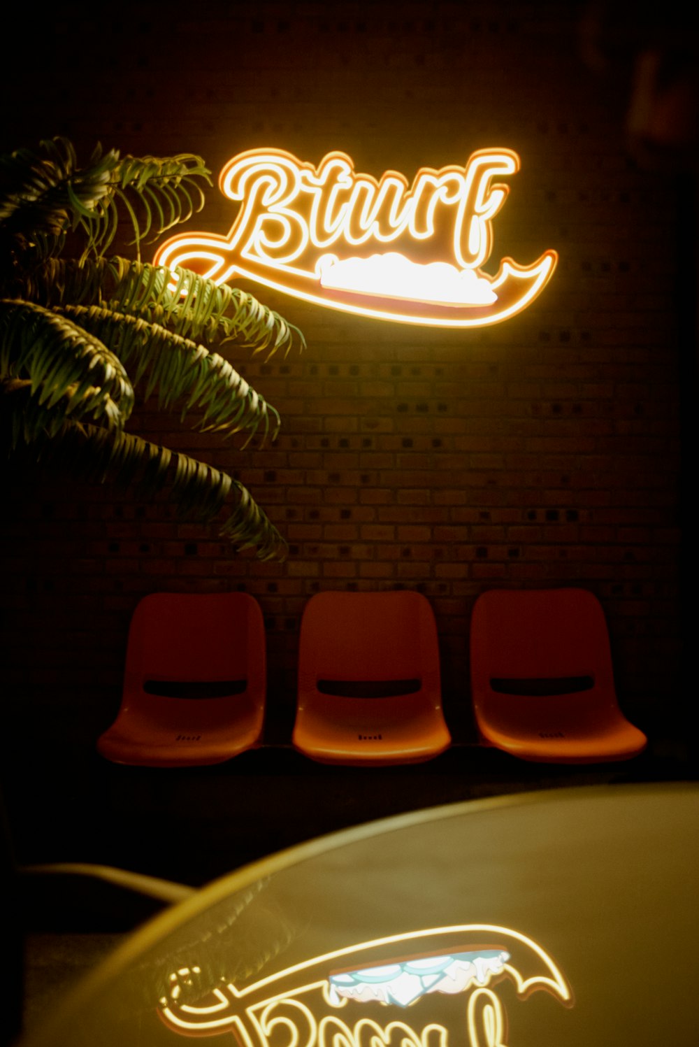 a neon sign above a row of red chairs