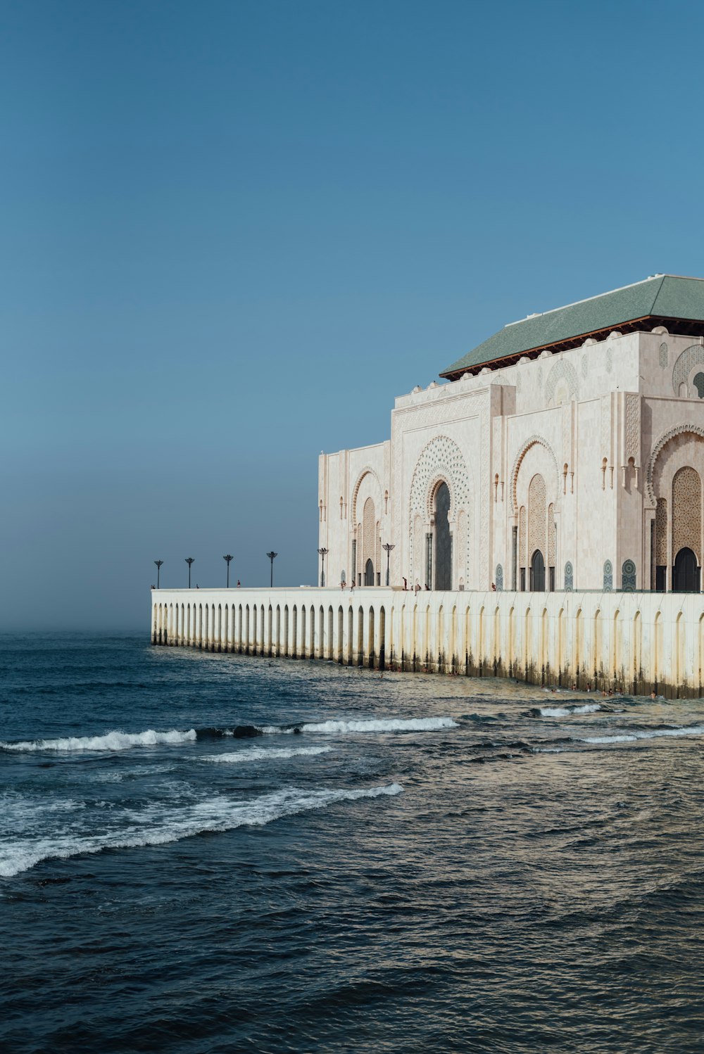 Un grand bâtiment assis au sommet d’une plage à côté de l’océan