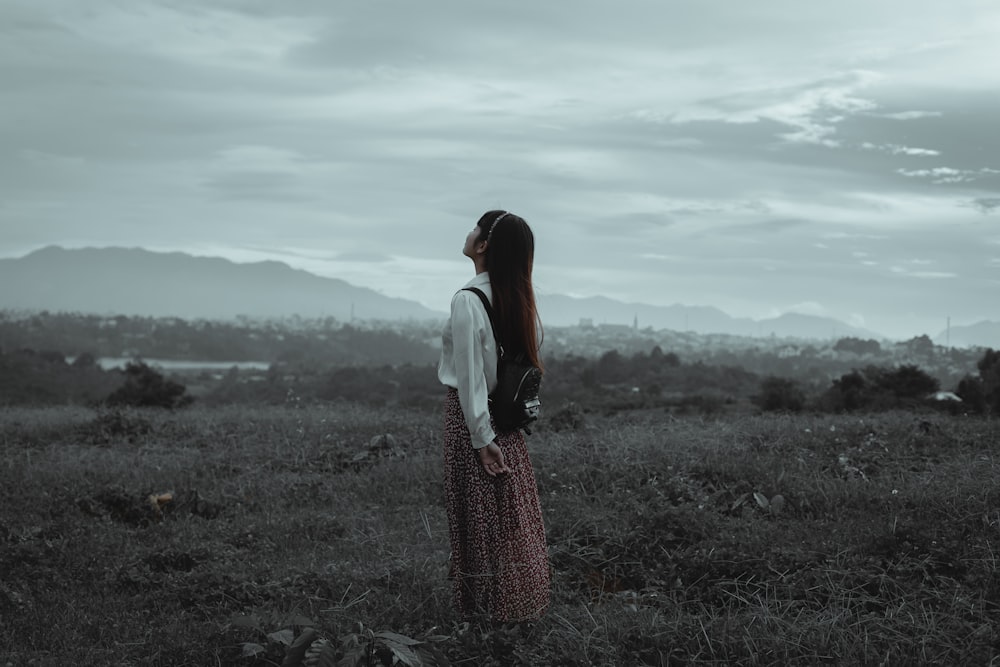 uma mulher em pé em um campo olhando para o céu