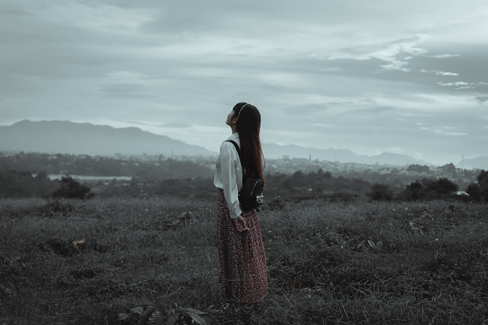 a woman standing in a field looking at the sky