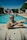 a man with tattoos sitting in front of a swimming pool