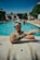 a man with tattoos sitting in front of a swimming pool