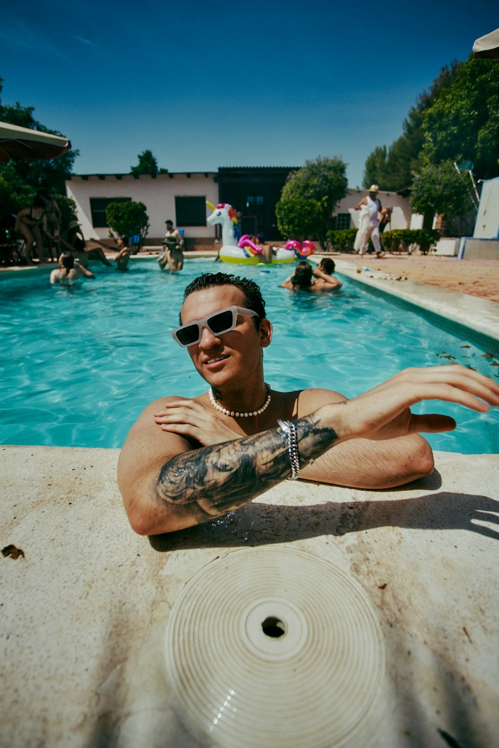 a man with tattoos sitting in front of a swimming pool
