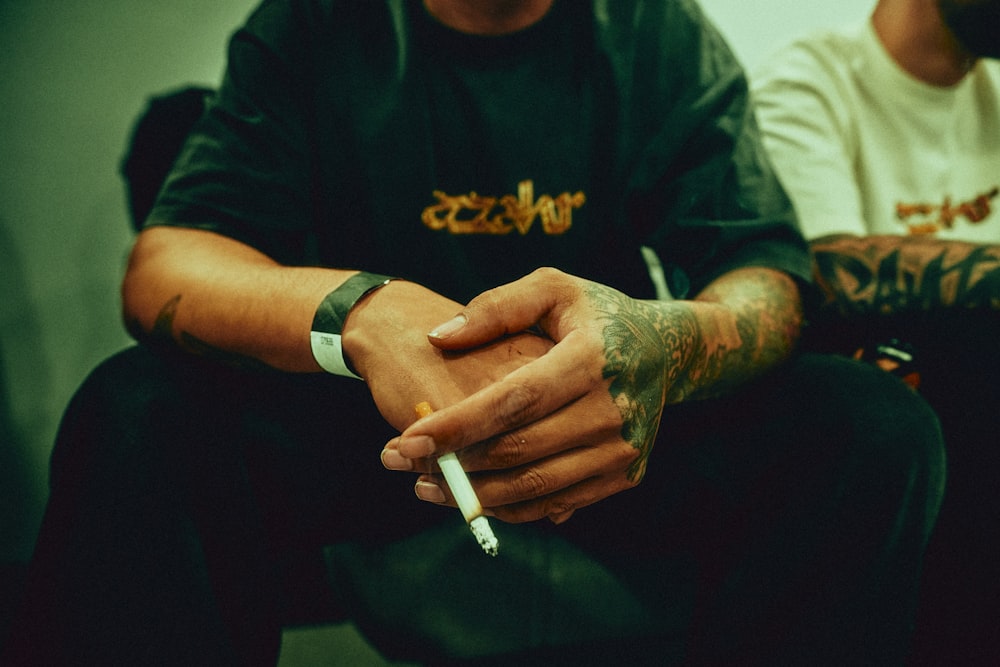 a man sitting down with a cigarette in his hand