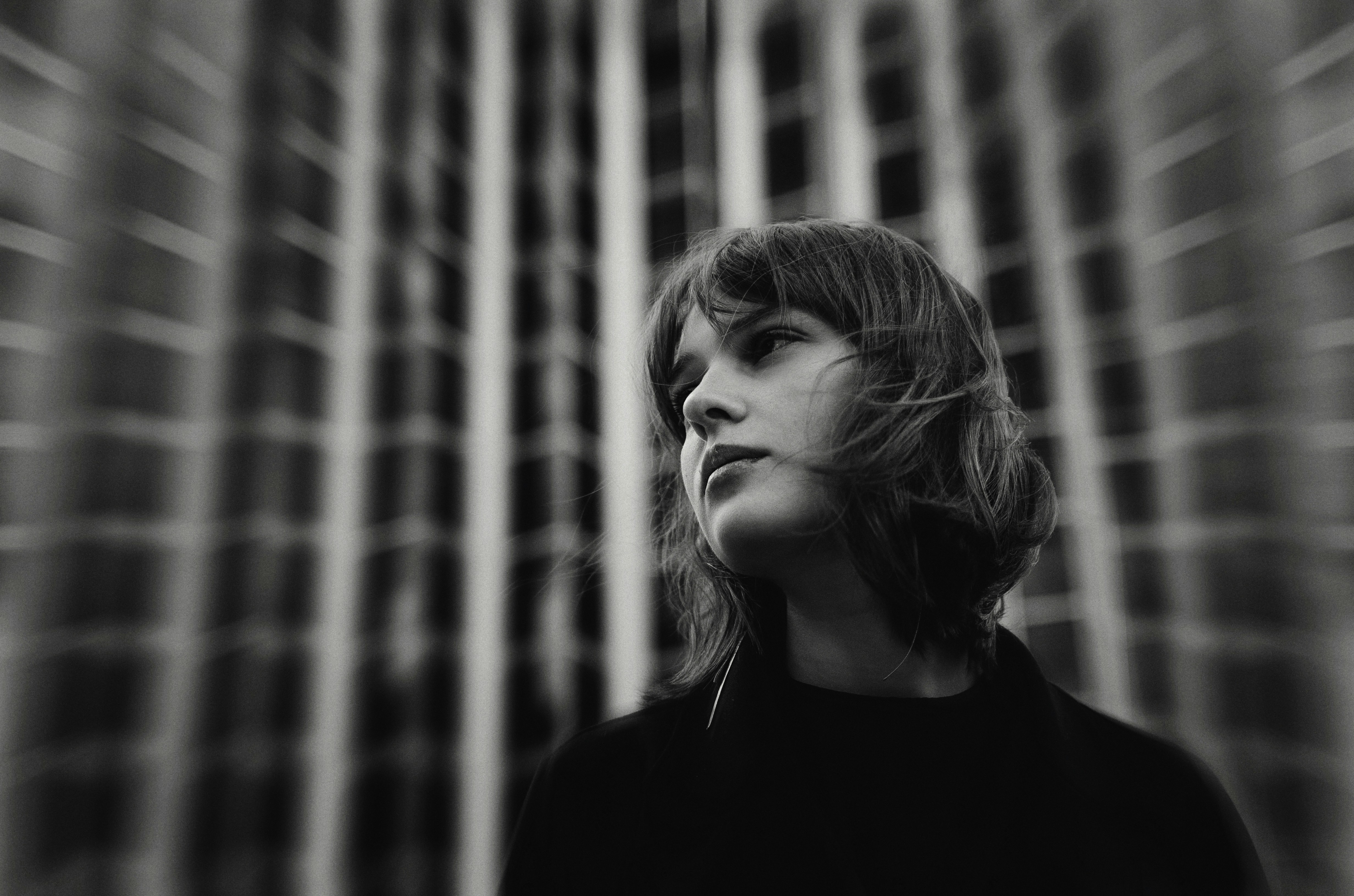 a black and white photo of a woman in front of a curtain