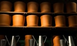 Close-up of colorful ceramic pots arranged on a wooden shelf under natural sunlight.
