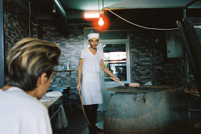 Technician carefully repairing a commercial oven in a busy restaurant kitchen.