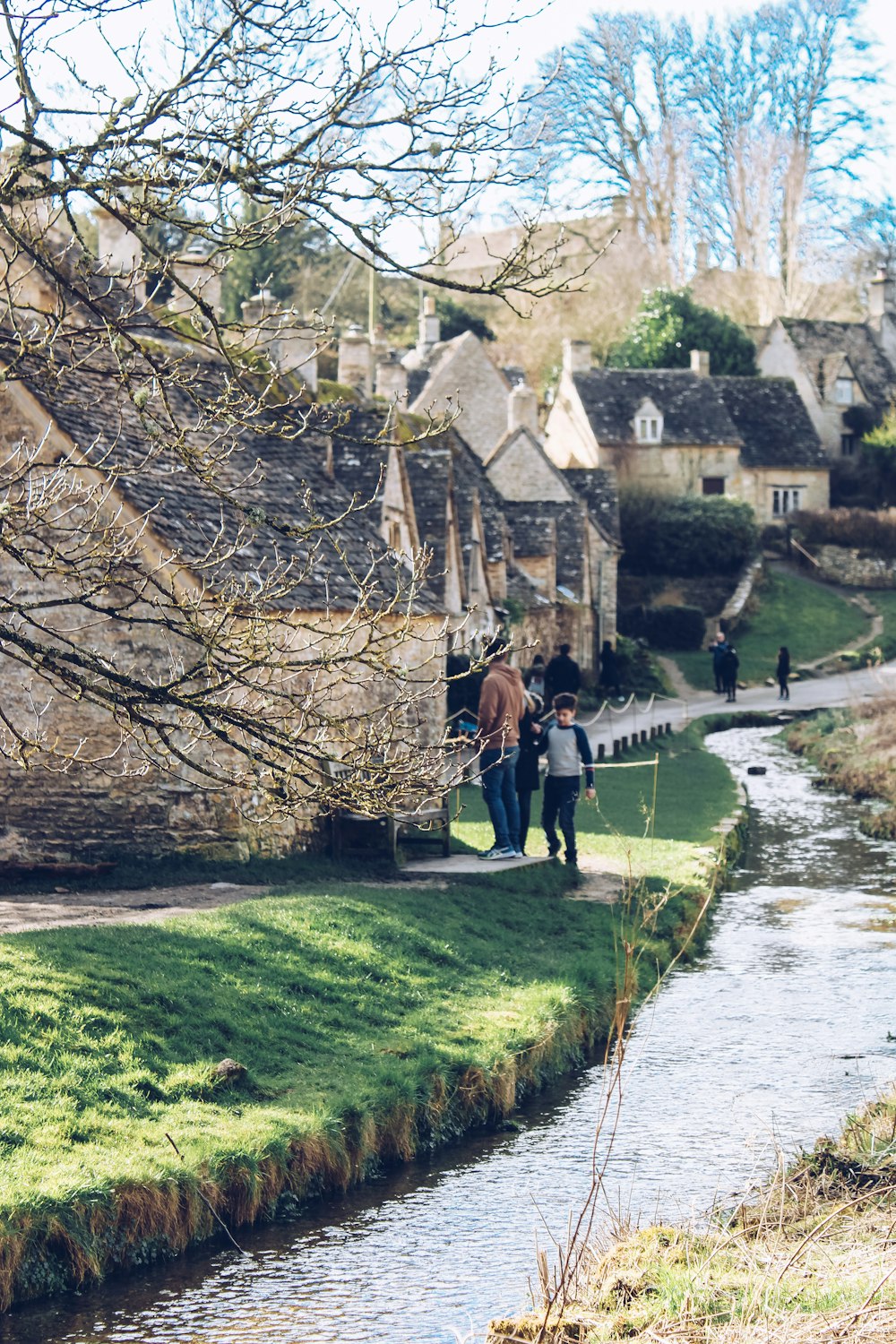 a couple of people walking down a street next to a river