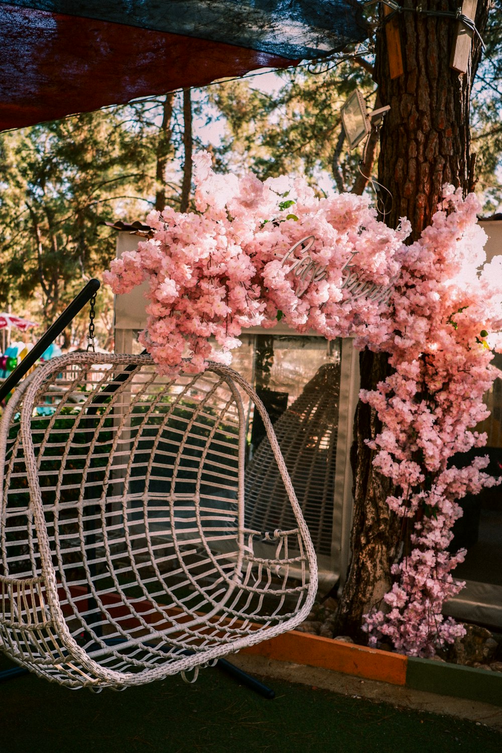 a bird cage with pink flowers hanging from it
