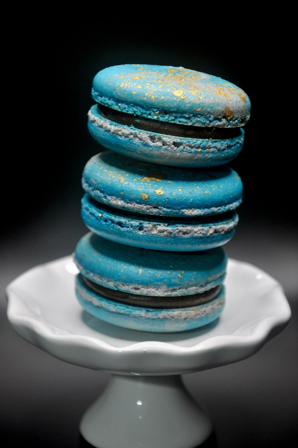 a stack of blue macaroons sitting on top of a white plate